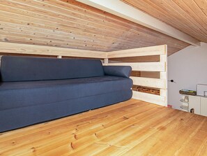 A modern loft bedroom with a built-in sofa, wooden slats, and a wooden floor. - 4 Person Holiday Home in Aeroskobing (Aeroskobing)
