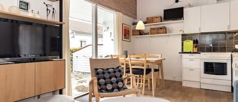 A modern kitchen with wooden cabinets, a built-in oven, and a dining area with a table and chairs.