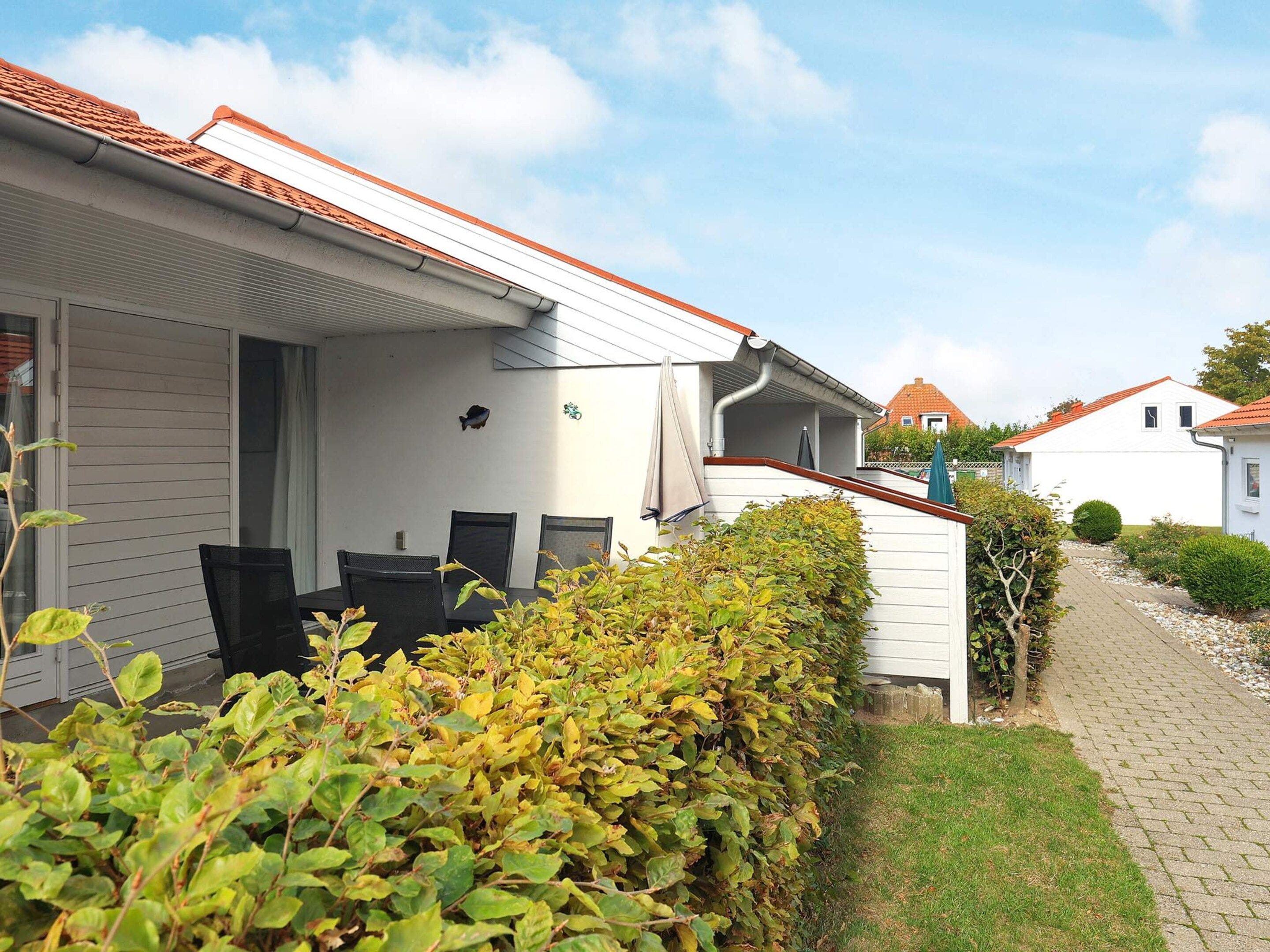 Ein Wohnhaus mit überdachter Terrasse, weißer Fassade und roten Ziegeln.