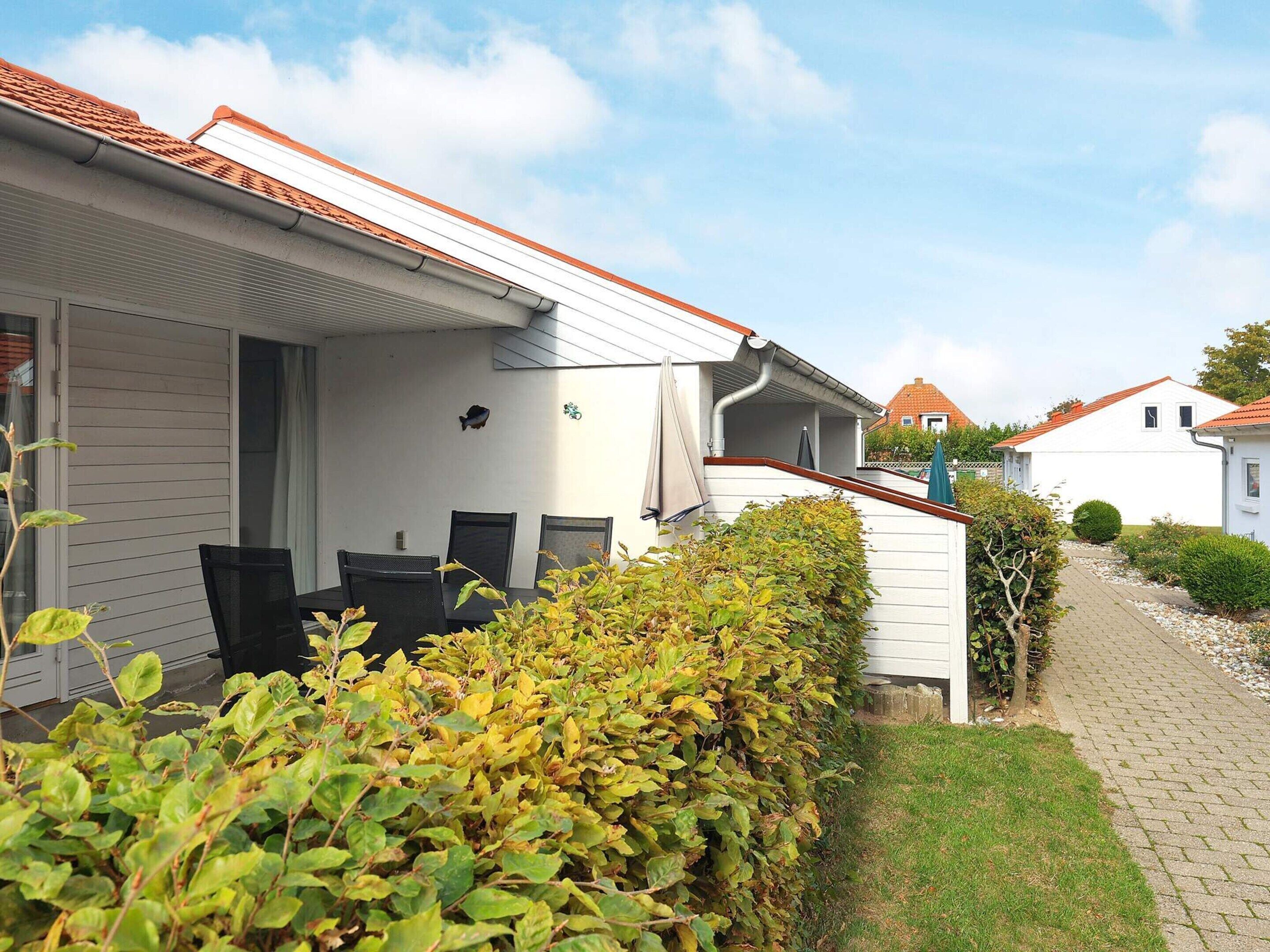 A residential house with a covered patio, a small garden, and a pathway leading to another house.