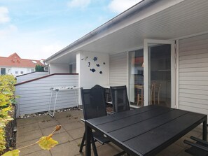 A patio with a table and chairs, a clothesline, and decorative fish wall art. - 4 Person Holiday Home in Aeroskobing (Aeroskobing)