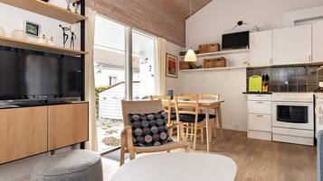 Une cuisine moderne dotée d’un grand téléviseur, de meubles en bois et d’un coin repas avec une table et des chaises.