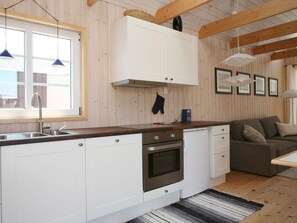 A modern kitchen with white cabinets, a built-in oven, and a wooden countertop. - 4 Star Holiday Home in Karrebaeksminde (Karrebæksminde)