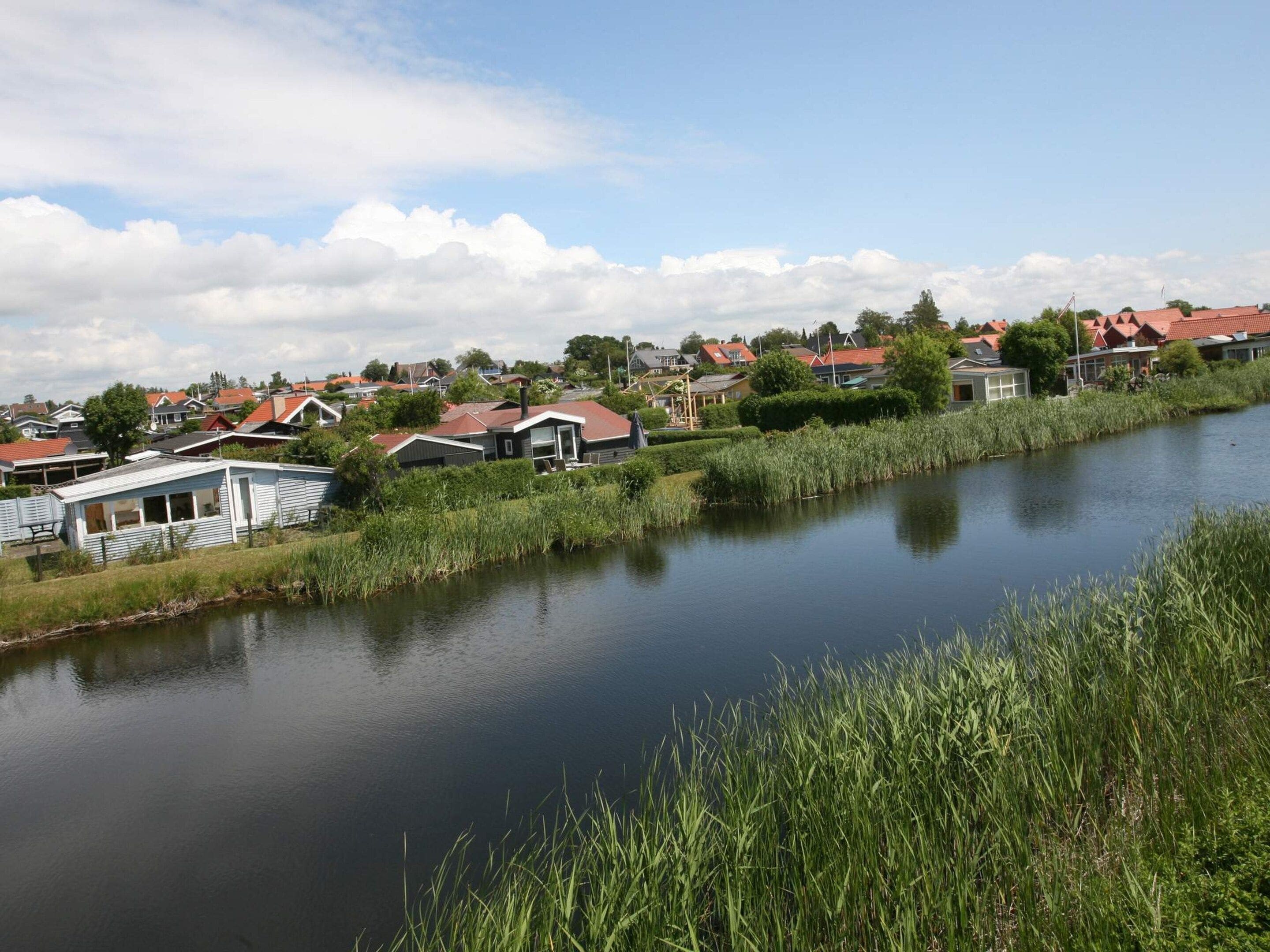 A calm river with houses on one side and a grassy area on the other.