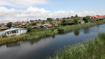 A calm river with houses on one side and a grassy area on the other.