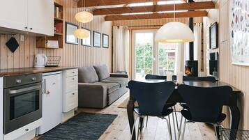 A modern kitchen with wooden beams, a dining area with chairs, a sofa, and a fireplace.
