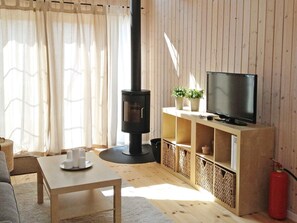 A cozy living room with a fireplace, a television on a wooden stand, a sofa, and a coffee table. - 4 Star Holiday Home in Karrebaeksminde (Karrebæksminde)