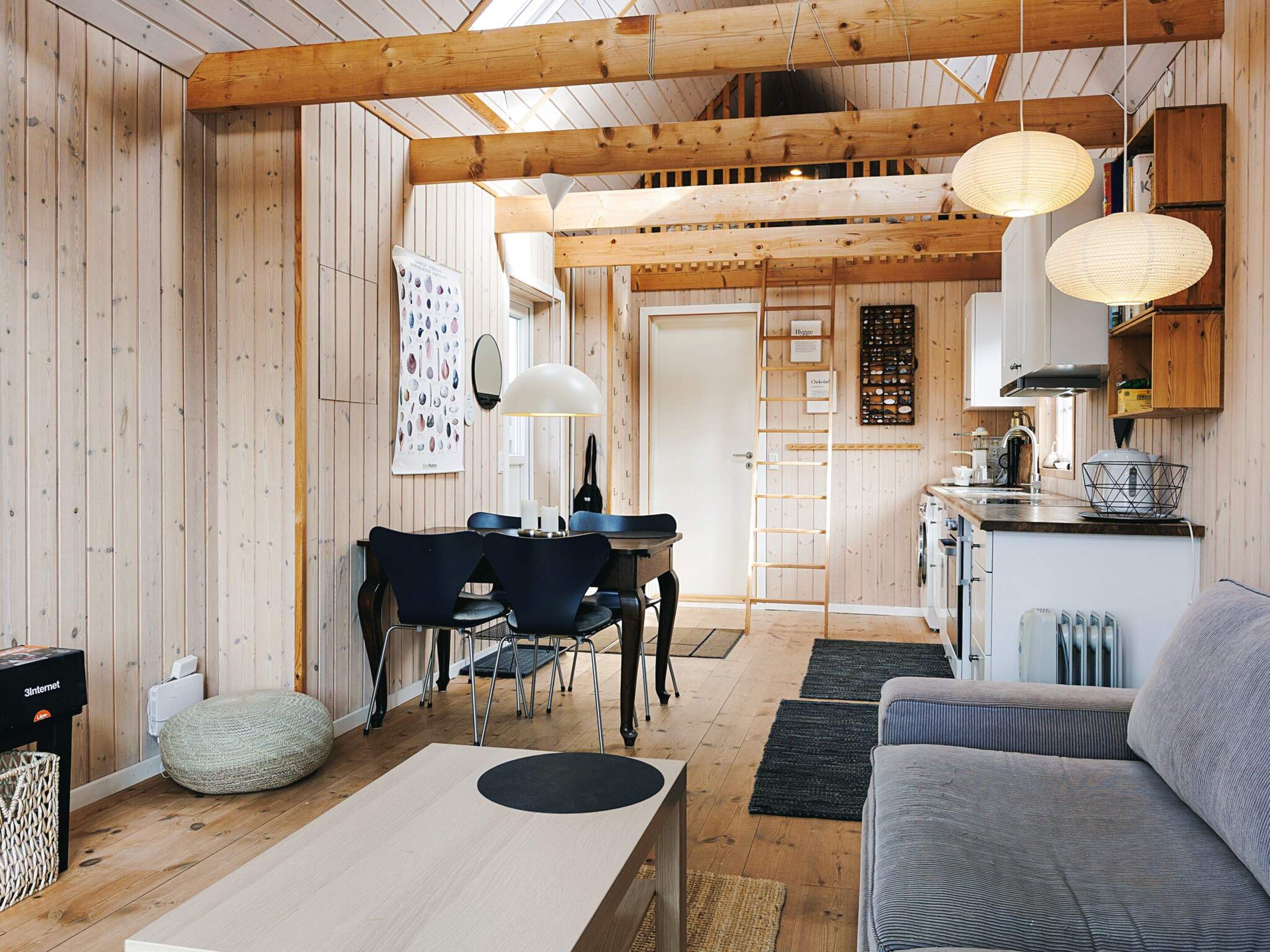 A cozy interior with a wooden dining area, a sofa, and a kitchen in the background.