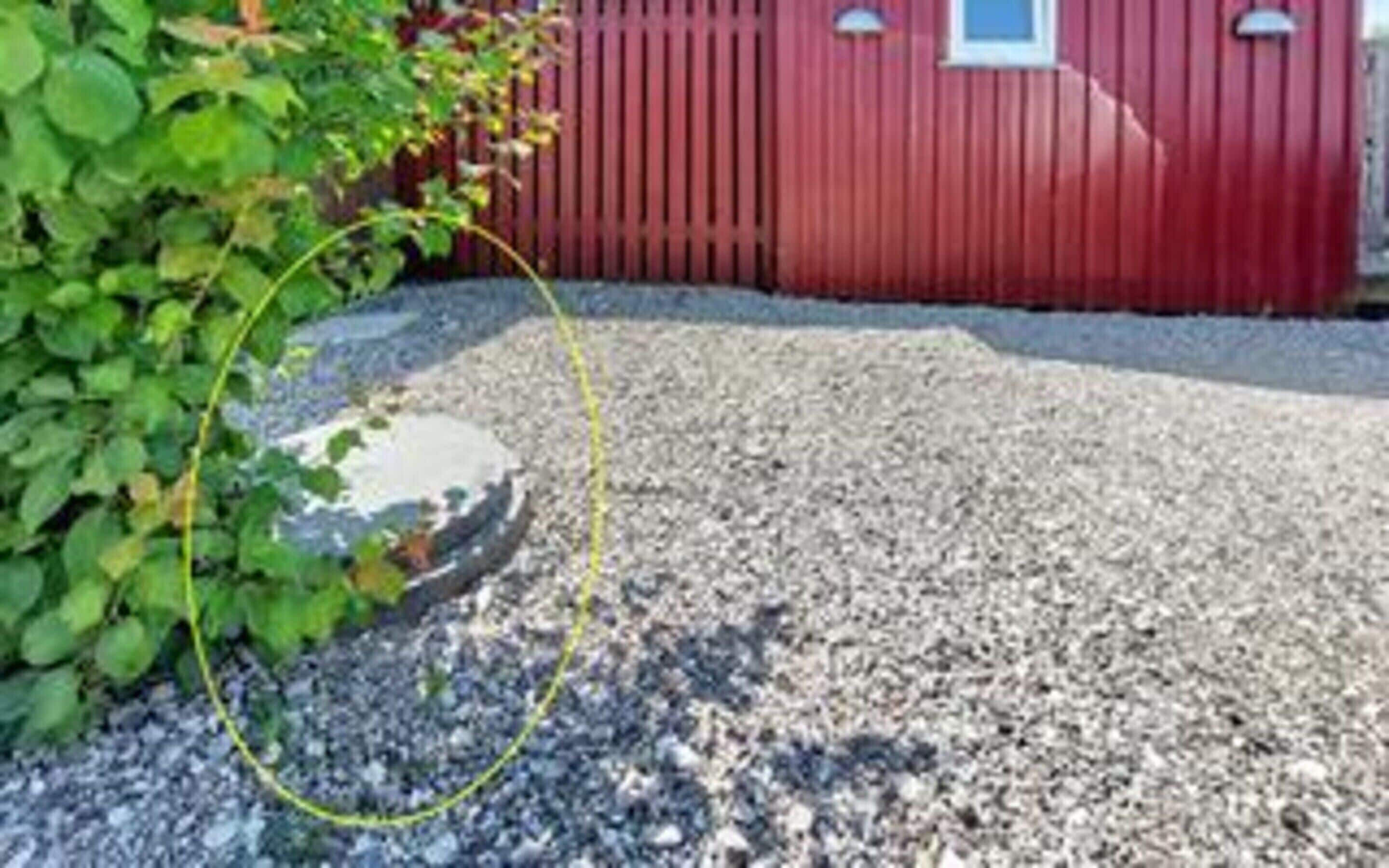 A gravel driveway leading to a red building with a window.