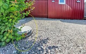 En grusuppfart leder fram till en röd byggnad med ett fönster.