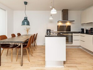 Una cocina moderna con una isla central, electrodomésticos de acero inoxidable y un comedor con mesa y sillas de madera.