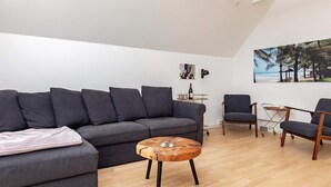 A modern living room with a grey sofa, a wooden coffee table, and two armchairs. - 4 Star Holiday Home in Vaeggerlose (Vaeggerlose)