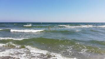 A beach with waves and people in the water.