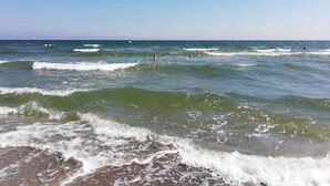 A beach with waves and people in the water. - 4 Star Holiday Home in Vaeggerlose (Vaeggerlose)