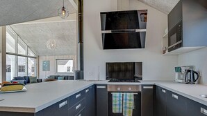 A modern kitchen with a central island, built-in oven, microwave, and coffee maker. - Holiday Home in Kappeln (Kappeln)