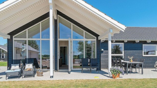 A modern house with a glass-enclosed patio, outdoor seating, and a clear sky. - Holiday Home in Kappeln (Kappeln)
