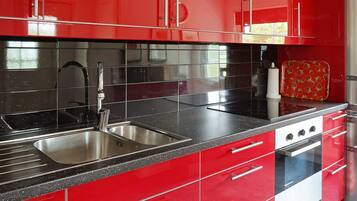 Una cocina moderna con armarios rojos, electrodomésticos de acero inoxidable y encimeras negras.