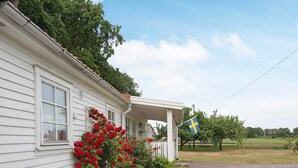 A white house with a porch, red flowers, and a Swedish flag. - 4 Person Holiday Home in Tvaaker (Tvaaker)