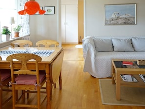 A cozy living room with a wooden dining table, a sofa, and a coffee table.