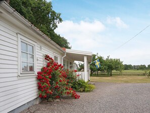 A white house with a porch, red flowers, and a Swedish flag. - 4 Person Holiday Home in Tvaaker (Tvaaker)