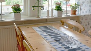 A room with a wooden table, a bench, and a window with curtains. - 4 Person Holiday Home in Tvaaker (Tvaaker)