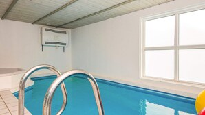An indoor swimming pool with metal ladders, a ceiling fan, and a window. - 4 Star Holiday Home in Nordborg (Nordborg)