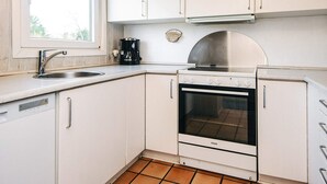 A compact kitchen with white cabinets, a stainless steel sink, a coffee maker, and a Voss oven. - 4 Star Holiday Home in Nordborg (Nordborg)