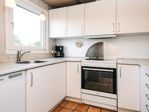 A compact kitchen with white cabinets, a stainless steel sink, a coffee maker, and a Voss oven. - 4 Star Holiday Home in Nordborg (Nordborg)