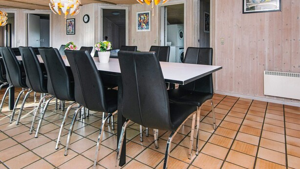 A dining area with a long table, black chairs, and two spherical chandeliers. - 4 Star Holiday Home in Nordborg (Nordborg)