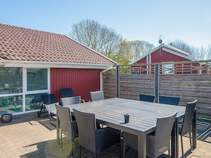 A patio with a table and chairs, a red building, and a wooden fence. - 4 Star Holiday Home in Nordborg (Nordborg)
