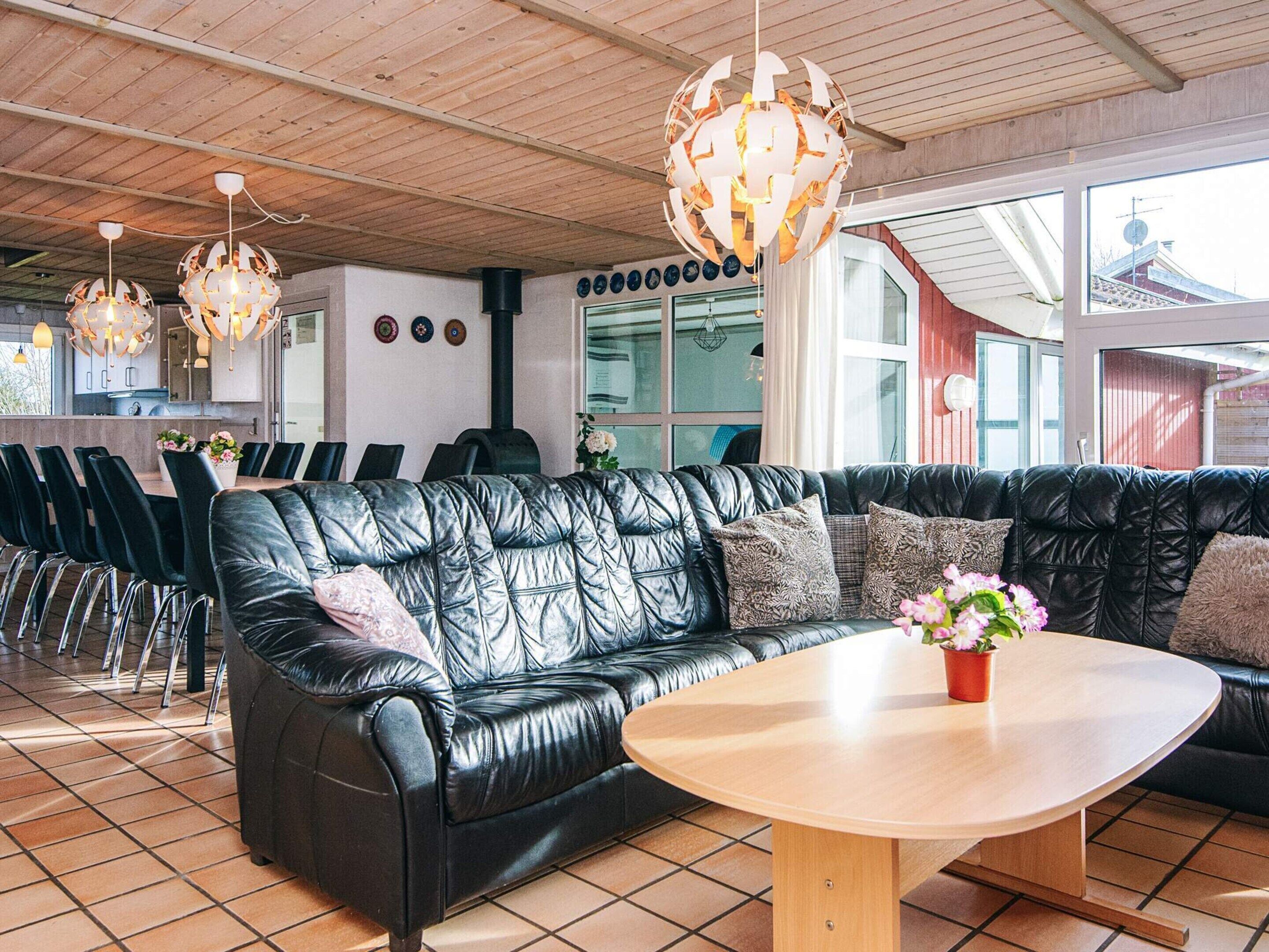 A modern interior with a black leather sofa, a wooden table, and pendant lights.