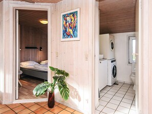 A compact room with a bed, a washing machine, and a potted plant.
