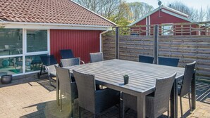 A patio with a table and chairs, a red building, and a wooden fence. - 4 Star Holiday Home in Nordborg (Nordborg)