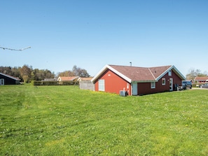 A red building with a sloped roof, a small attached structure, and a grassy field. - 4 Star Holiday Home in Nordborg (Nordborg)