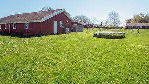 A red barn with a sloped roof, a trampoline, and a grassy field. - 4 Star Holiday Home in Nordborg (Nordborg)