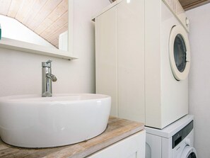 A bathroom with a white sink, a mirror, and a washing machine. - 4 Star Holiday Home in Nordborg (Nordborg)
