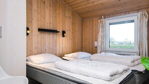 A room with a large bed, a chair, and a window with curtains. - 4 Star Holiday Home in Nordborg (Nordborg)