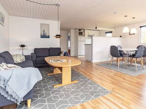 Un espace de vie moderne comprenant un canapé, une table ronde en bois et un coin repas avec des chaises.