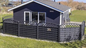 A small, dark-colored cabin with a number '35' on the gate, a covered porch, and a sign reading 'Klitten.' - 4 Person Holiday Home in Lokken (Lokken)