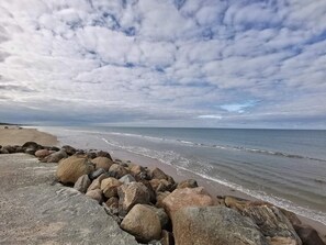 Une plage bordée d’une côte rocheuse, sous un ciel nuageux.