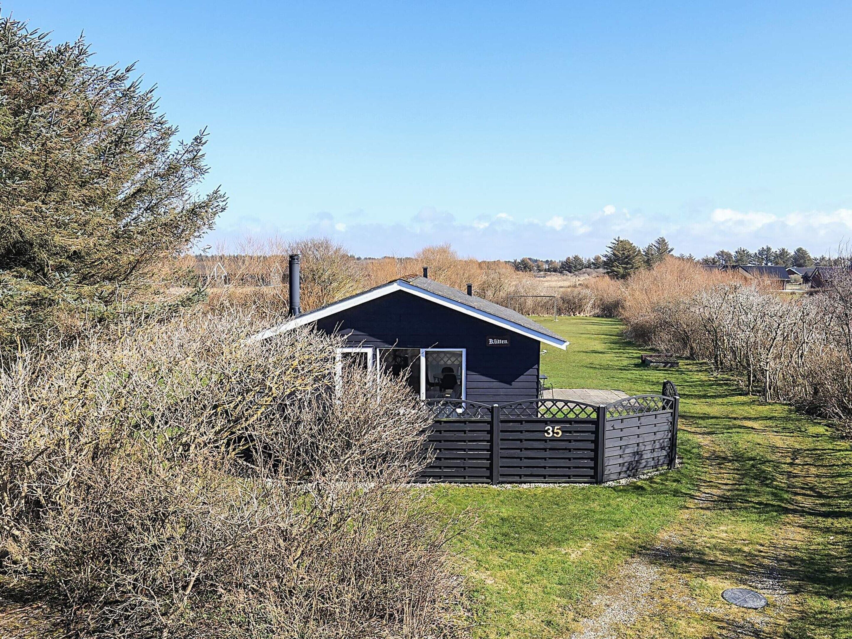A small cabin with a dark exterior, a chimney, and a number '35' on the gate.
