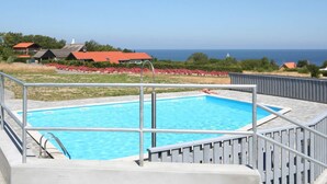 Una piscina con vista al mar y casas al fondo.