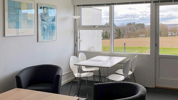 A room with a large window, a table, and two chairs.