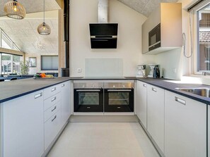A modern kitchen with two ovens, a built-in microwave, and a large window. - Holiday Home in Kappeln (Kappeln)