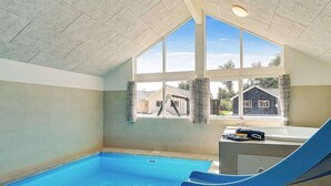 An indoor swimming pool with a slide, large windows, and a view of houses outside. - Holiday Home in Kappeln (Kappeln)