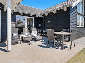 Une terrasse avec des meubles d’extérieur, un barbecue et une table.