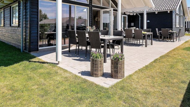 A modern outdoor patio area with tables and chairs, large windows, and a covered seating area. - Holiday Home in Kappeln (Kappeln)