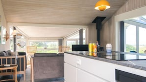 A modern kitchen with a large island, wooden flooring, and a view of the outdoors.