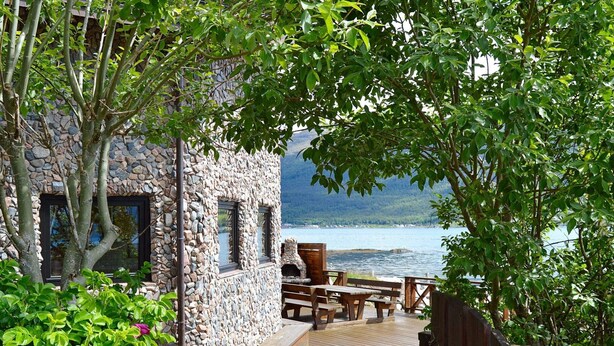 A stone building with a wooden deck and outdoor seating area overlooking a lake. - Holiday Home in EidsvÃ¥g (Molde)