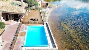 A swimming pool with a wooden deck, a covered seating area, and a view of a lake. - Holiday Home in EidsvÃ¥g (Molde)